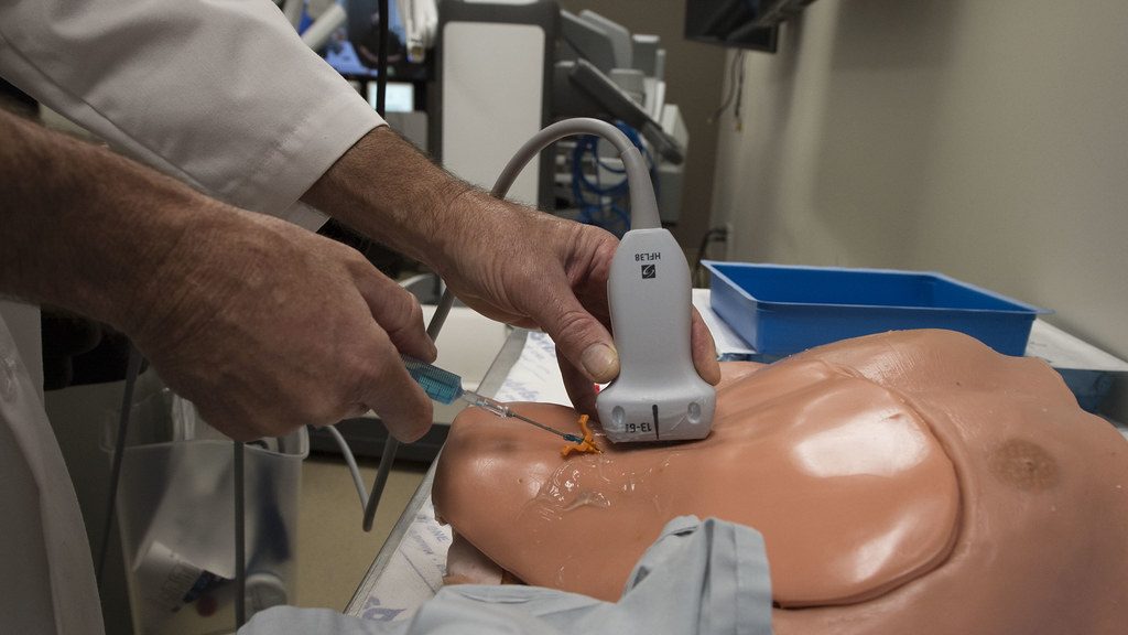 Mão segurando o transdutor sobre um simulador de treino